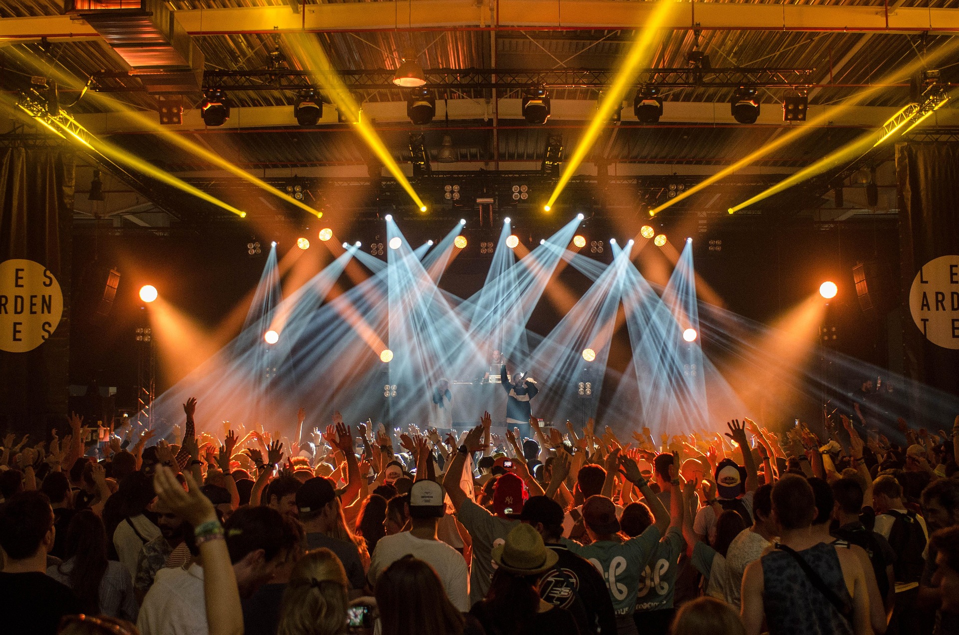 Night Parade on stage under yellow and white lights, crowd with hands raised